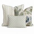 The Blue Garden Thistle Green Trio Throw Pillow Bundle by Hillcroft Home features three decorative pillows: one with green stripes and border, another with a green and blue floral pattern, and a smaller front pillow showcasing a pale green fan-inspired geometric design. All are elegantly arranged together on a white background.