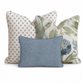The Blue Garden Thistle Navy Trio Throw Pillow Bundle by Hillcroft Home features three decorative pillows: one with a small blue floral pattern, one with a green and blue leafy floral print, and a smaller blue pillow with a dotted design, all set against a white background.