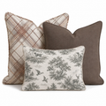 The Hillcroft Home Hunting Toile Trio Throw Pillow Bundle features three decorative pillows—one in plaid, one in solid brown, and one cream pillow adorned with a black nature and animal print—beautifully arranged together against a white background.