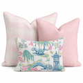 The Lotus & Willow Trio Throw Pillow Bundle by Hillcroft Home features three decorative pillows: two large pillows—one with a pink check pattern and one in solid pink—and a smaller front pillow adorned with a floral and pagoda print in pink, green, blue, and white. All are arranged against a white background.