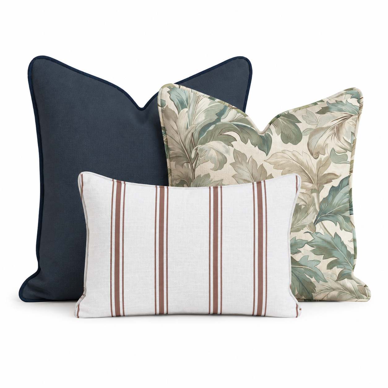 The Cordelia Trio Throw Pillow Bundle by Hillcroft Home features three decorative pillows—one solid navy, one with a green leaf pattern, and one rectangular white pillow with brown stripes—arranged together on a white background.