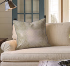A beige couch with a large, square Hillcroft Home Dotted Powder Fawn Throw Pillow, crafted from a linen blend and made in the USA, sits in a cozy living room with a blue door and a lamp nearby.