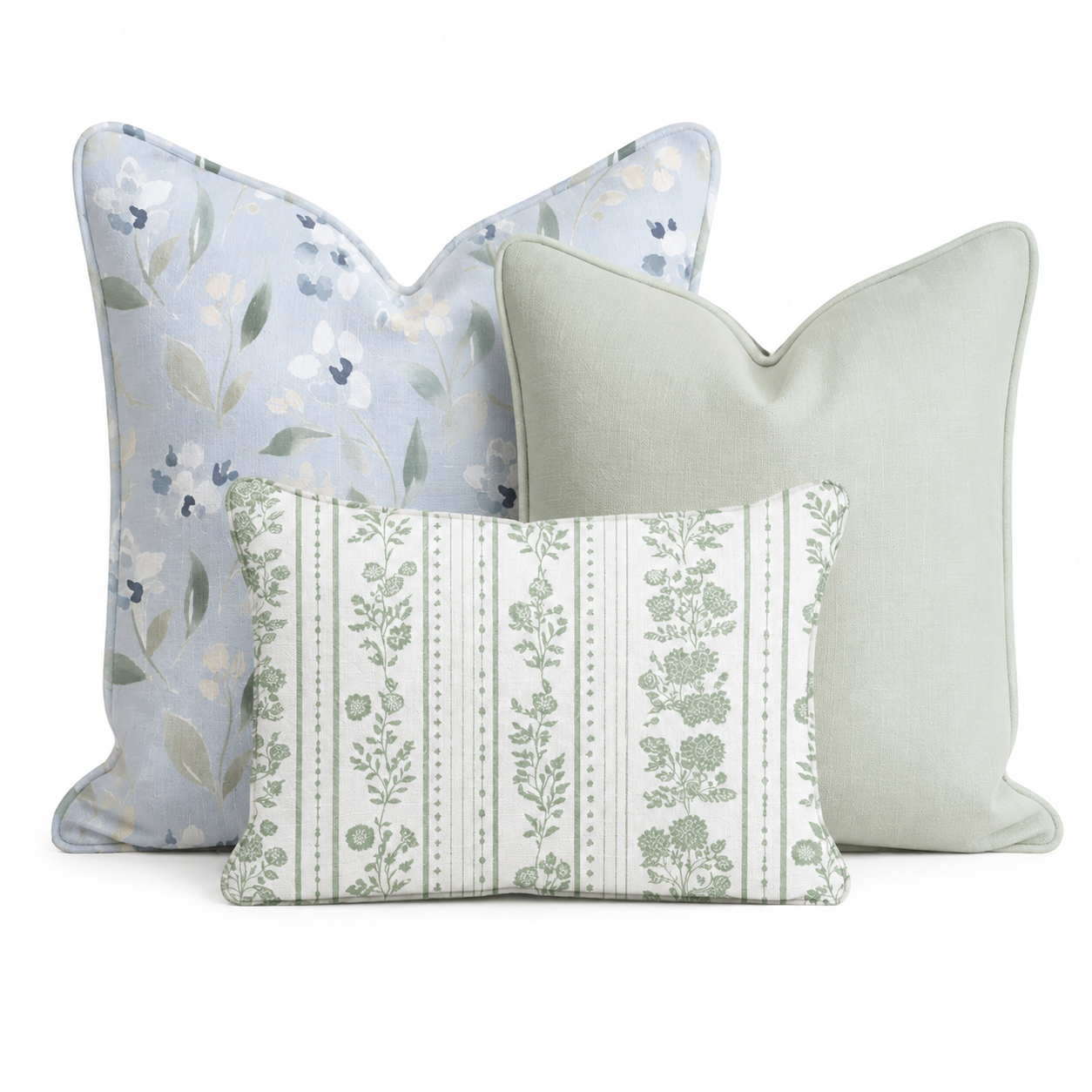 The Hillcroft Home Golf Trip Floral Trio Throw Pillow Bundle features three decorative pillows—a pale blue pillow with a floral pattern, a solid light green pillow, and a rectangular pillow adorned with green floral and stripe patterns—arranged against a white background.
