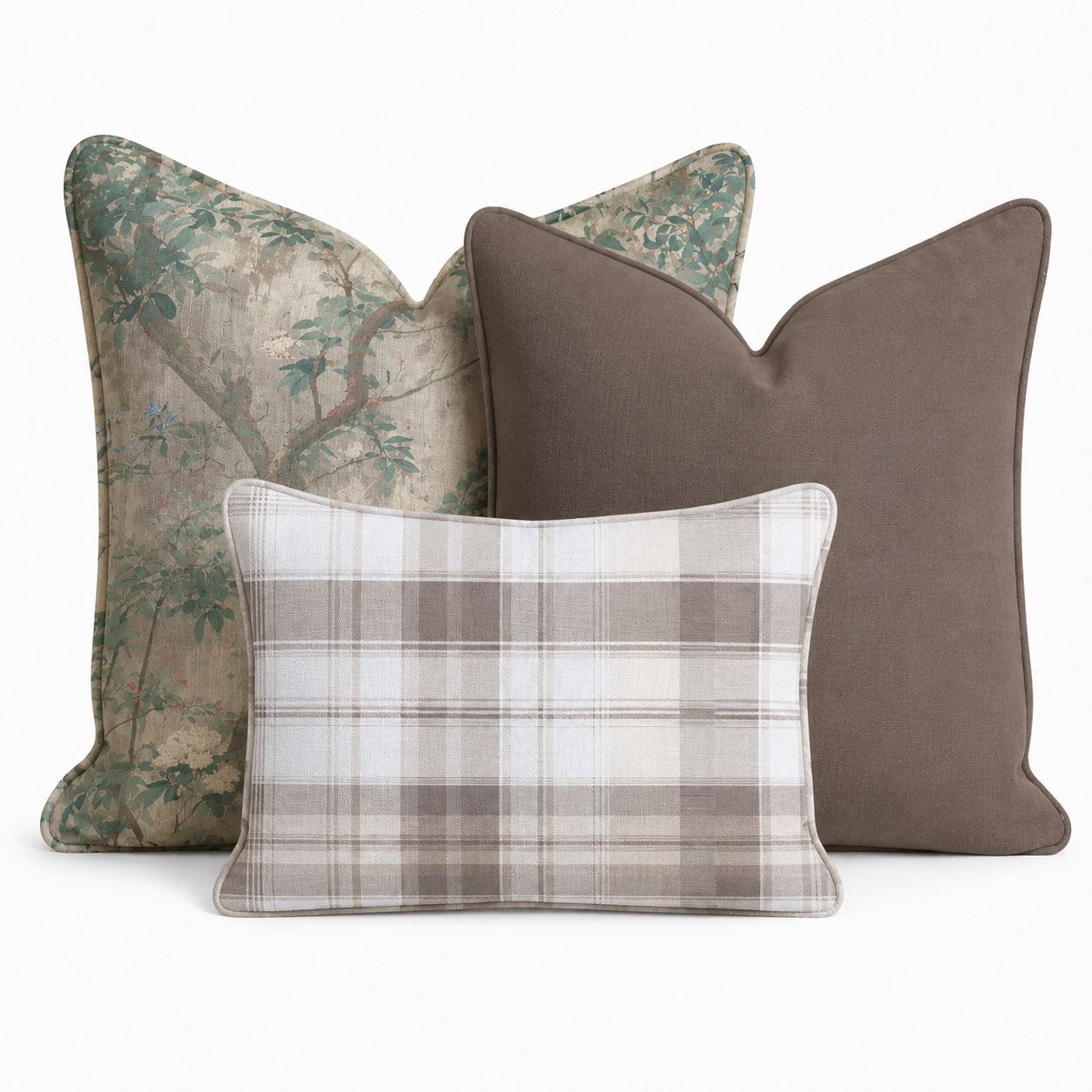 The Hedgerow Trio Throw Pillow Bundle by Hillcroft Home features three decorative pillows—one with a green floral pattern, one solid brown, and one in a beige and gray plaid design—arranged together against a plain white background.